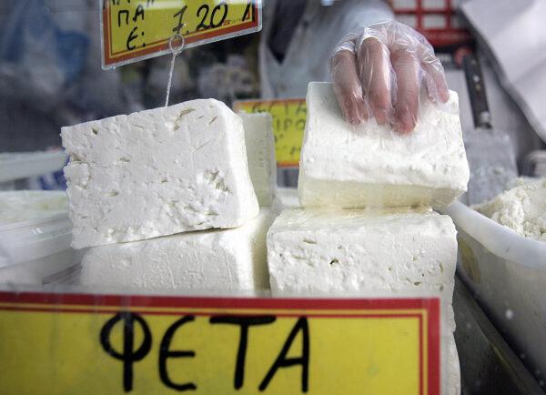 A shop assistant lifts a slab of feta cheese in Athens, Greece, on Oct. 25, 2005. (Aris Messinis/AFP via Getty Images)