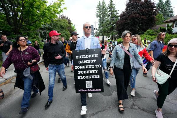 Chris Elston (C), also called "Billboard Chris," carries a billboard surrounded by supporters during a protest against gender ideology in Ottawa on June 9, 2023. (The Canadian Press/Sean Kilpatrick)