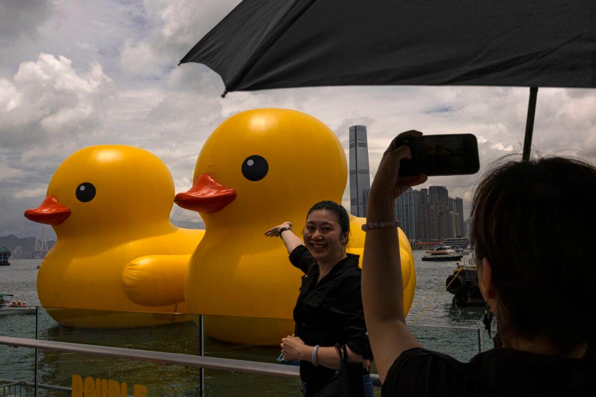 Members of the public photograph an art installation called "Double Ducks" by Dutch artist Florentijn Hofman at Victoria Harbor in Hong Kong on June 9, 2023. (AP Photo/Louise Delmotte)