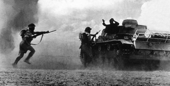 Two soldiers belonging to the Commonwealth and Allied forces aim at a German soldier surrendering atop his tank in 1942 in North Africa. (AFP via Getty Images)