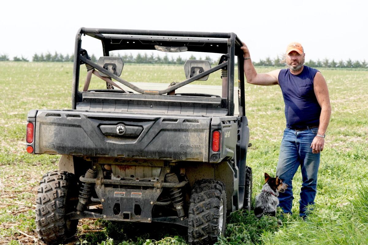 Fourth-generation South Dakota farmer Jared Bossly leans against his all-wheel-drive vehicle on his farm on June 10, 2023. (Allan Stein/The Epoch Times)