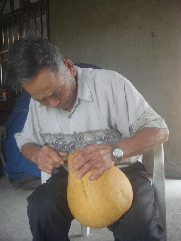 Crescent's father works on a gourd. (Courtesy of Gan Jing World)