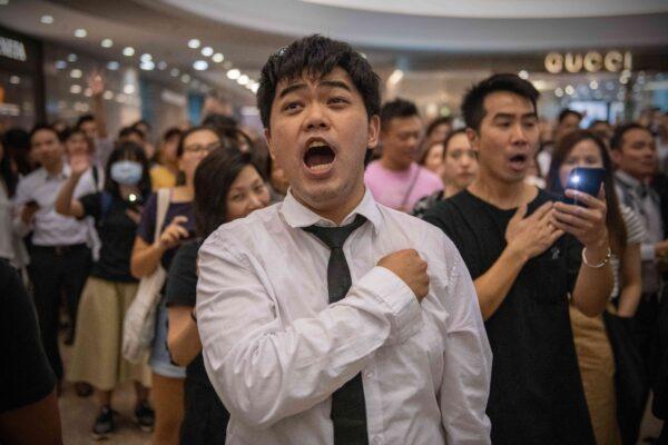 A protester holds his hand against his chest as he sings the Glory to Hong Kong protest "anthem" during a demonstration in Times Square shopping mall in Hong Kong on Sept. 12, 2019. (Carl Court/Getty Images)