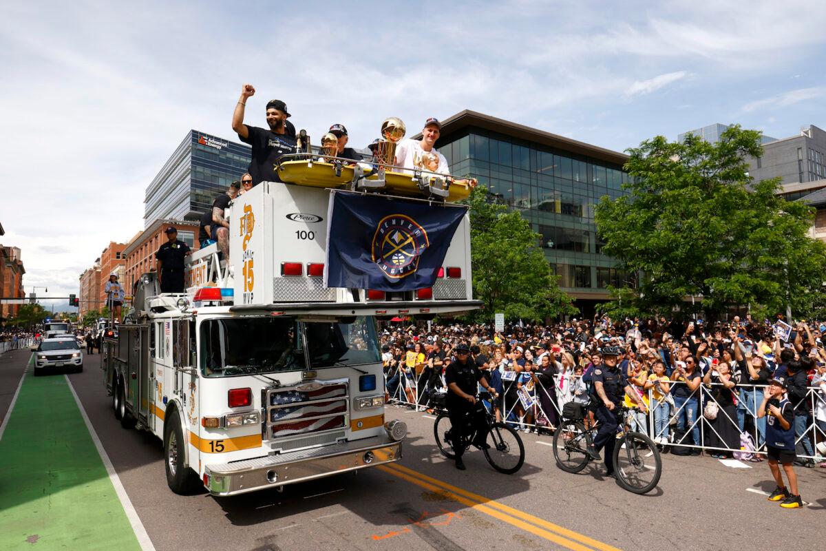 Jamal Murray #27 and Nikola Jokic #15 wave to fans with the Larry O'Brien Championship Trophy during the Denver Nuggets victory parade and rally after winning the 2023 NBA Championship in Denver, Colo., on June 15, 2023. (Justin Edmonds/Getty Images)