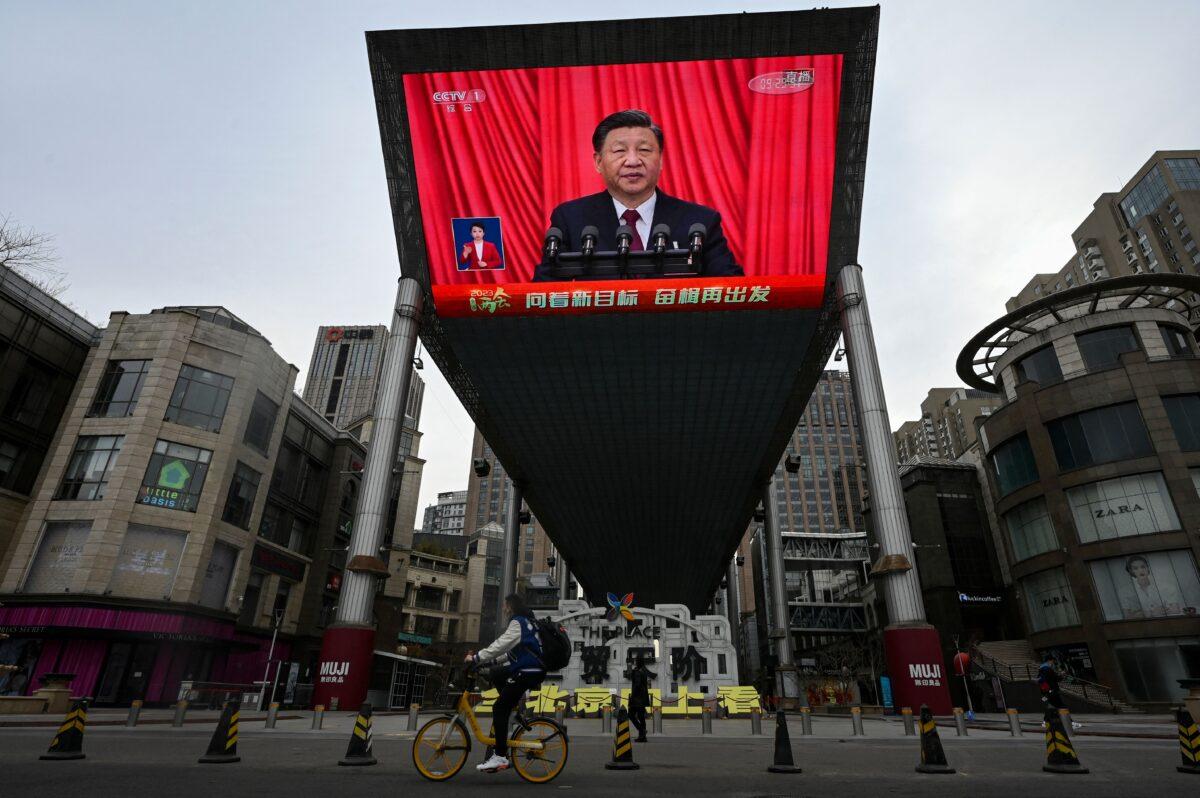 An outdoor screen shows live news coverage of China's leader Xi Jinping delivering a speech during the closing session of the National People's Congress (NPC) at the Great Hall of the People, along a street in Beijing on March 13, 2023. (Jade Gao/AFP via Getty Images)