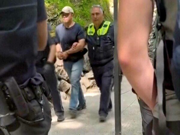 In this image taken from video, a suspect is taken away by two police officers near Neuschwanstein castle in Schwangau, southern Germany, on June 15, 2023. (Eric Abneri via AP)