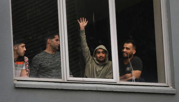 Asylum seekers gesture from their hotel room where they were detained in Melbourne on June 13, 2020. (William West/AFP via Getty Images)