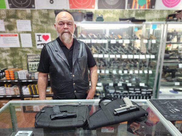 Tom Van Hoose, owner of Highwood Creek Outfitters in Great Falls, Mont., shows a pair of semi-automatic handguns on June 20, 2023. (Allan Stein/The Epoch Times)