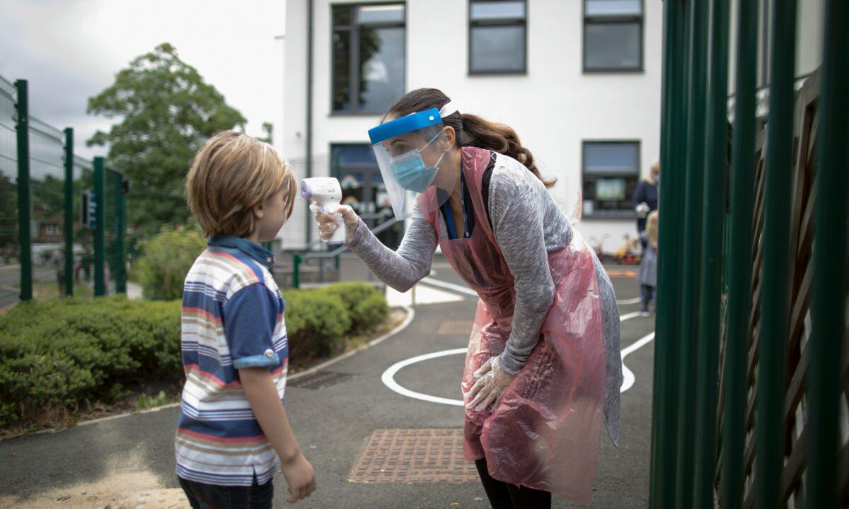 A member of staff wearing personal protective equipment takes a child's temperature at the Harris Academy's Shortland's school in London on June 4, 2020. (Dan Kitwood/Getty Images)