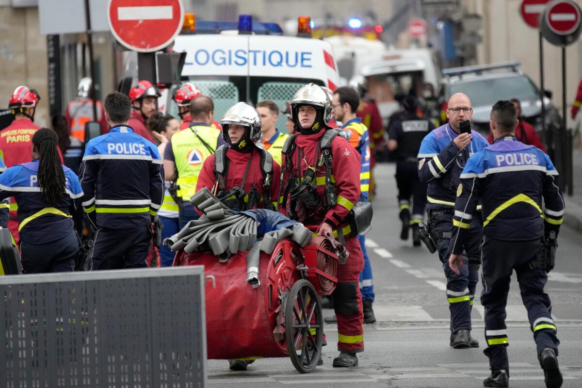 Police officers and rescue workers work at the site of a fire in Paris on June 21, 2023. (Christophe Ena/AP Photo)