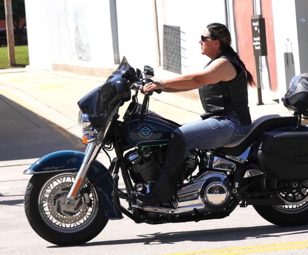 A female Harley-Davidson rider glides through downtown Sturgis, S.D., on June 17, 2023. (Allan Stein/The Epoch Times)