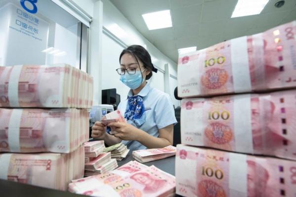 A bank employee counts 100-yuan notes at a bank counter in Nantong, in China's eastern Jiangsu Province, on June 13, 2023. (STR/AFP via Getty Images)