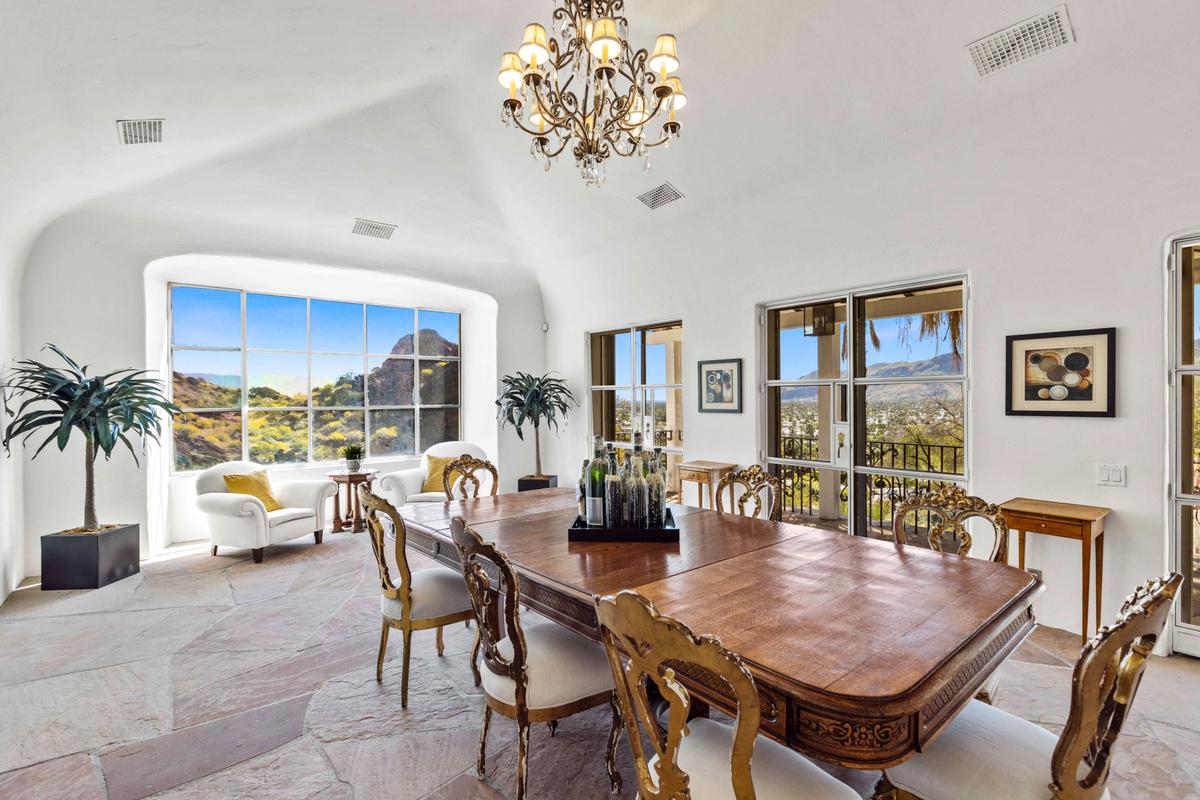The main residence’s dining room features stone flooring and vaulted ceiling accented with a vintage chandelier, while the generous number of windows provide a great view of the magnificent surroundings. (Courtesy of Kelly Peak, toptenrealestatedeals.com)