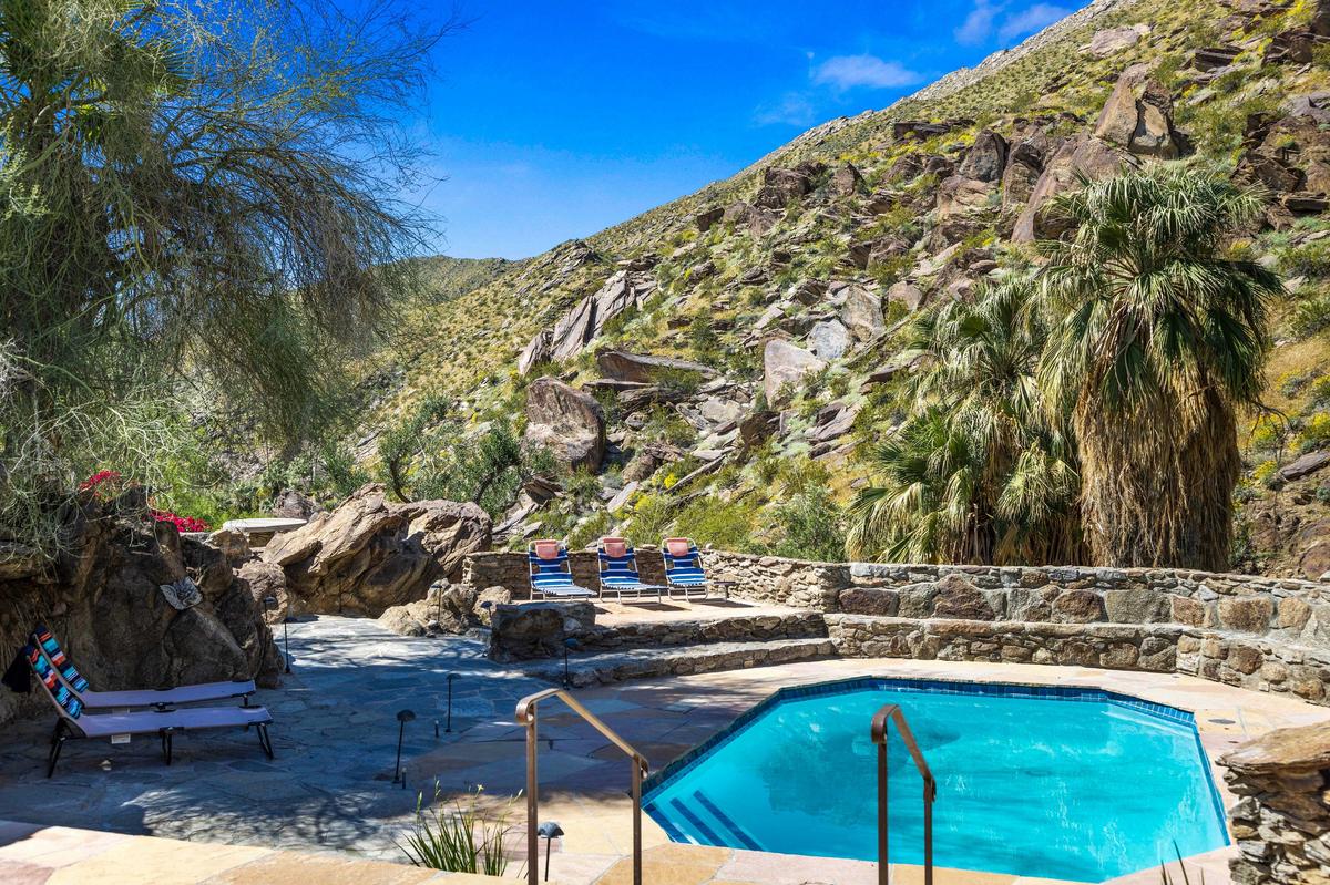 The pool, partially shaded by native trees and accented with locally sourced rock, looks out over the surrounding hills. (Courtesy of Kelly Peak, toptenrealestatedeals.com)
