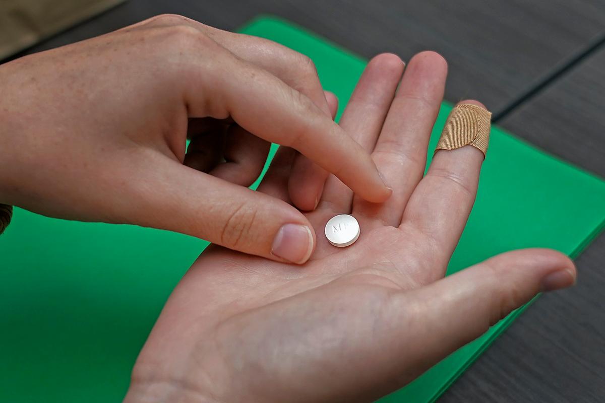 A patient prepares to take the first of two combination pills, mifepristone, for a medication abortion during a visit to a clinic in Kansas City, Kansas, on Oct. 12, 2022. (Charlie Riedel/AP Photo)