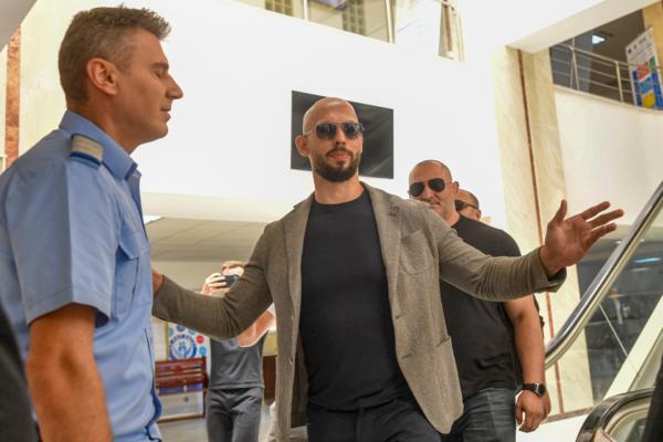 Andrew Tate gestures next to a gendarme as he leaves the Bucharest Tribunal, along with his brother Tristan (right) after the first hearing in their trial in Bucharest, Romania, on June 21, 2023. (Alexandru Dobre/AP Photo)