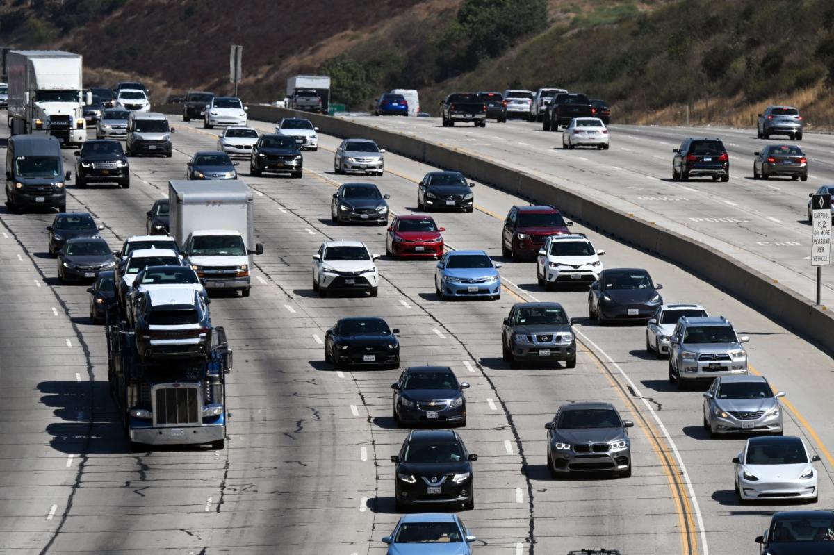 A truck pulls a car carrier trailer as cars, SUVs, and other vehicles drive in traffic on the 405 freeway through the Sepulveda Pass in Los Angeles on Aug. 25, 2022. (Patrick T. Fallon/AFP via Getty Images)