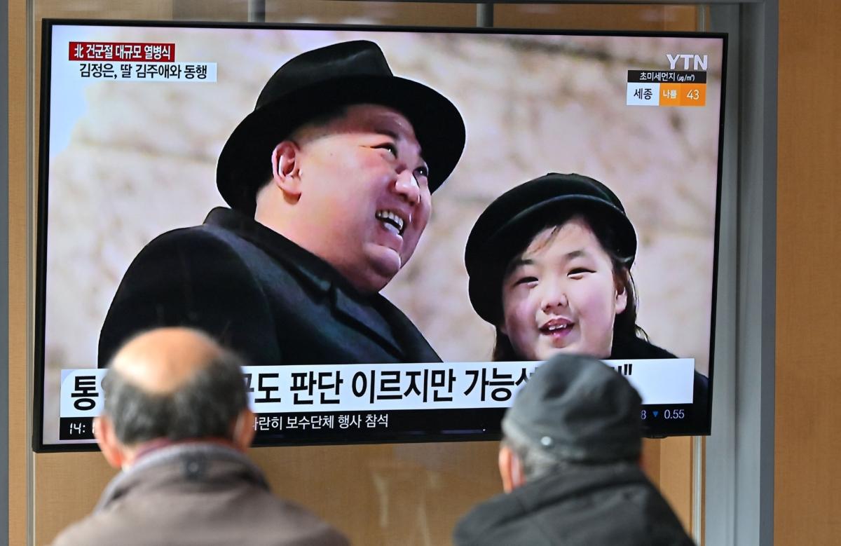 People watch a television screen showing a news broadcast with an image of North Korean leader Kim Jong Un (L) and his daughter presumed to be named Ju-ae (R) attending a military parade held in Pyongyang to mark the 75th founding anniversary of its armed forces, at a railway station in Seoul on Feb. 9, 2023. (Jung Yeon-je /AFP via Getty Images)