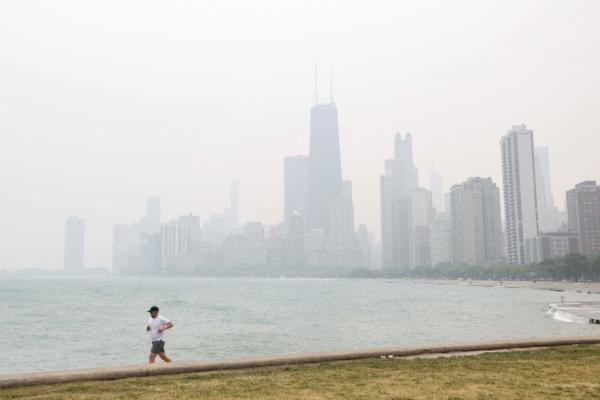 A jogger runs along the shoreline of Lake Michigan with heavy smoke from the Canadian wildfires in the background in Chicago on June 27, 2023. (Kamil Krzaczynski/AFP via Getty Images)