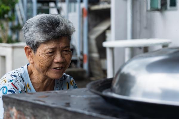 Auntie waits patiently for the dumplings to cook in the giant wok. (Benson Lau/The Epoch Times)