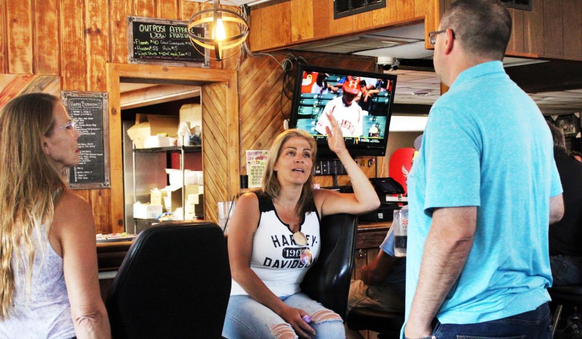 Lisa Monet Zarza (C) talks with customers at her new business, the Outpost Bar and Grill, in Bay City, Wis., on June 19, 2023. (Michael Clements/The Epoch Times)