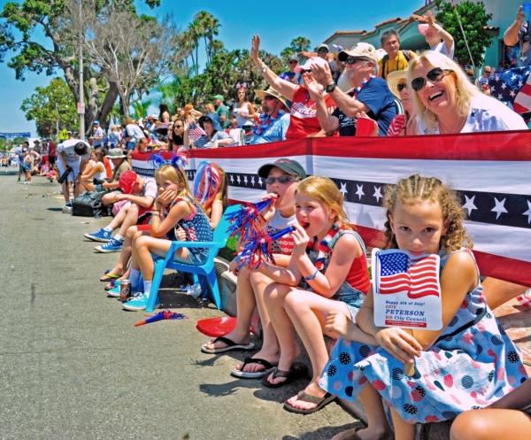 Families watch the Huntington Beach Independence Day Parade in Huntington Beach, Calif., on July 4, 2014. (Eric Zhang/The Epoch Times)