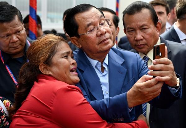 Cambodia's Prime Minister Hun Sen (C) takes selfies with a supporter during the inauguration ceremony of the Bakheng-1 water treatment plant in Phnom Penh, Cambodia, on June 19, 2023. (Tang Chhin Sothy/AFP via Getty Images)