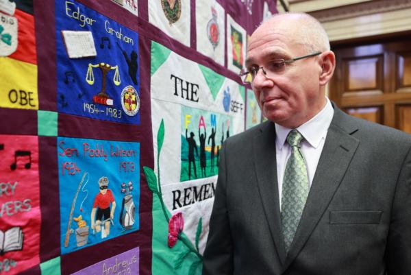 Paul Wilson, the son of Paddy Wilson, stands beside a memorial quilt created by the South East Fermanagh Foundation (SEFF) during an event in Stormont marking the 50th anniversary of the murder of his father SDLP senator Paddy Wilson on June 26, 2023. (Liam McBurney/PA Wire)