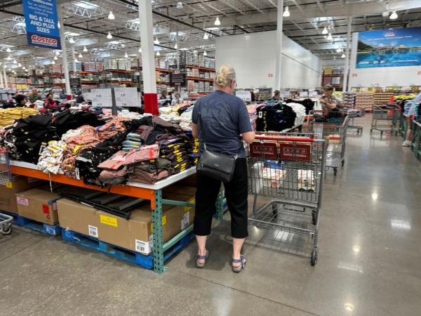 A shopper surveys stacks of clothing on a sales table in a Costco warehouse in Colorado Springs, Colo., on June 22, 2023. (David Zalubowski/AP Photo)