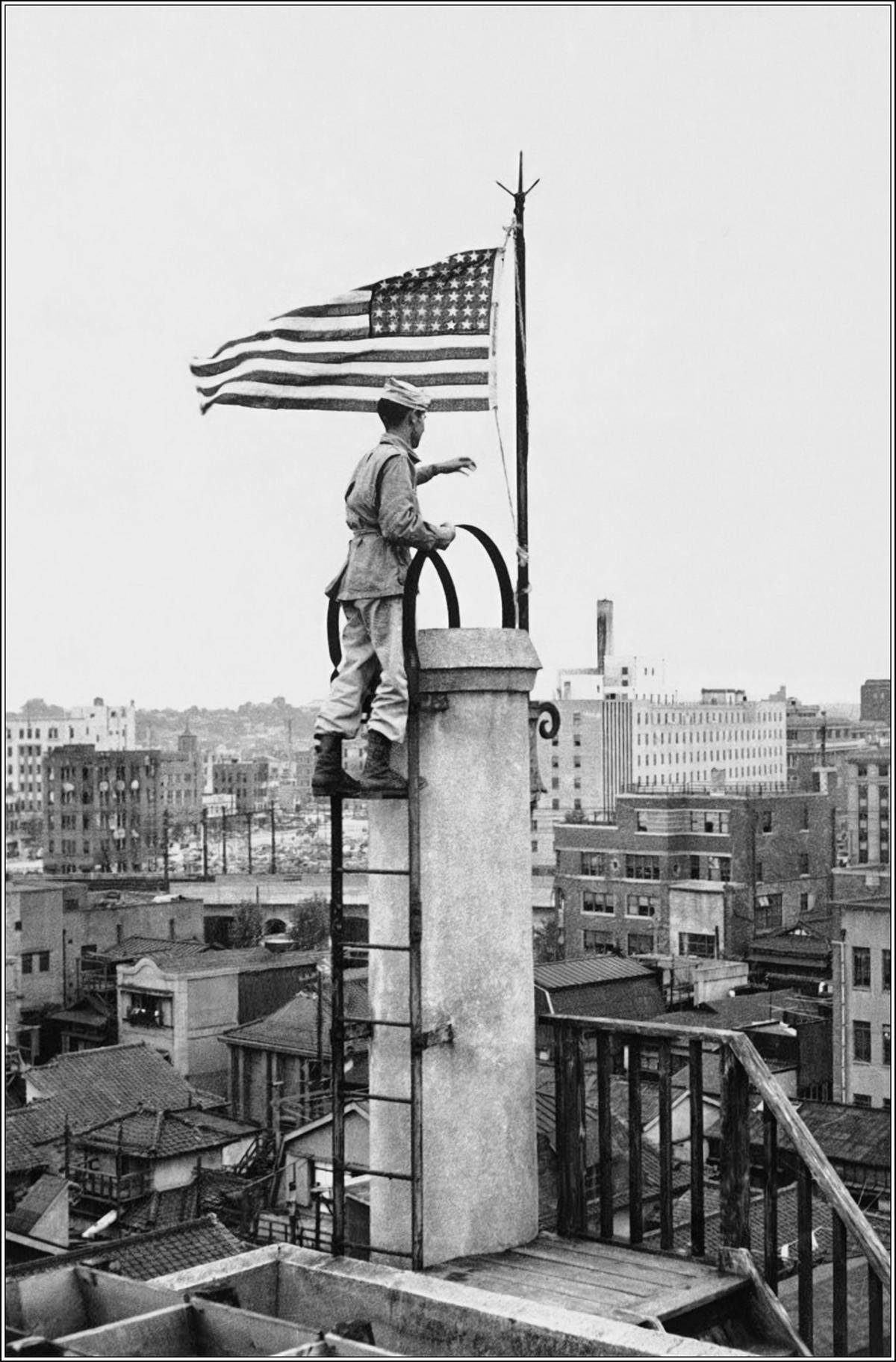 The Angels’ Lt. Bernard J. "Bud" Stapleton raises the American flag atop the Nippon News building in Tokyo on Sept. 5, 1945. (<span style="font-weight: 400;">U.S. Army Archives)</span>