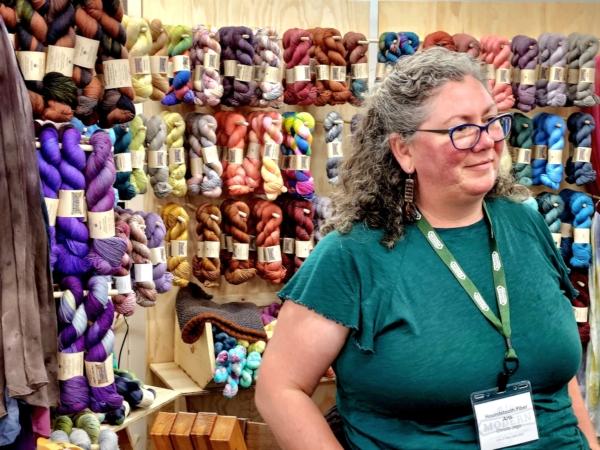A vendor stand in front of an assortment of wool yarn at The Modern Homesteading Conference in northern Idaho on June 30, 2023. (Allan Stein/The Epoch Times)