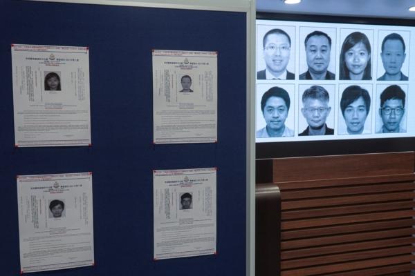 Photos of eight activists who have been issued arrest warrants over national security are displayed during a press conference in Hong Kong on July 3, 2023. (Joyce Zhou/Reuters)