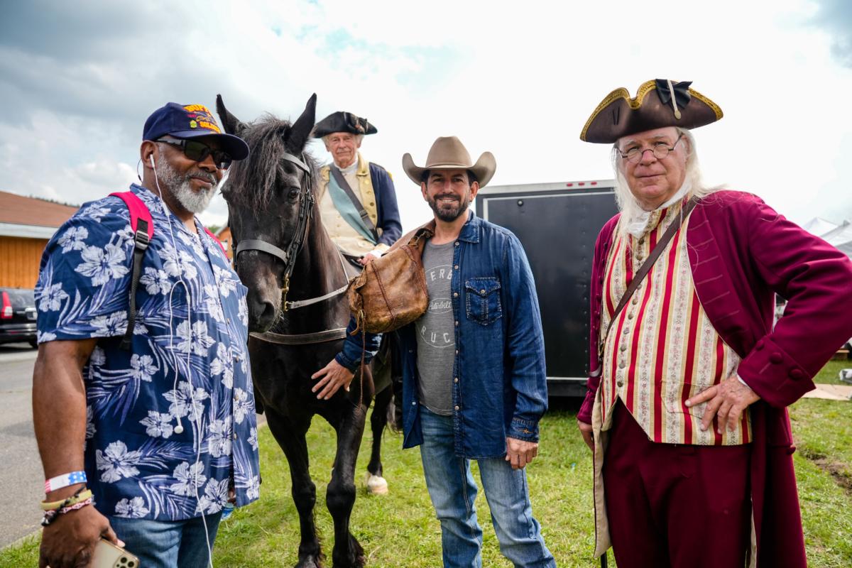 Command Sergeant Major Sa’eed Mustafa (L) and country singer Danny Griego (2nd R) pose with George Washington and Benjamin Franklin reenactors at America the Beautiful Festival in Deerpark, N.Y., on July 2, 2023. (Samira Bouaou/The Epoch Times)