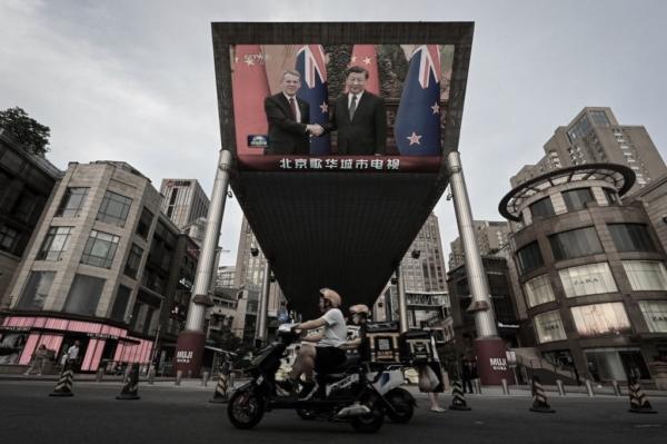 An outdoor screen shows news coverage of New Zealand's Prime Minister Chris Hipkins meeting with Chinese Leader Xi Jinping at the Great Hall of the People along a street in Beijing on June 27, 2023. (Jade Gao/AFP via Getty Images)