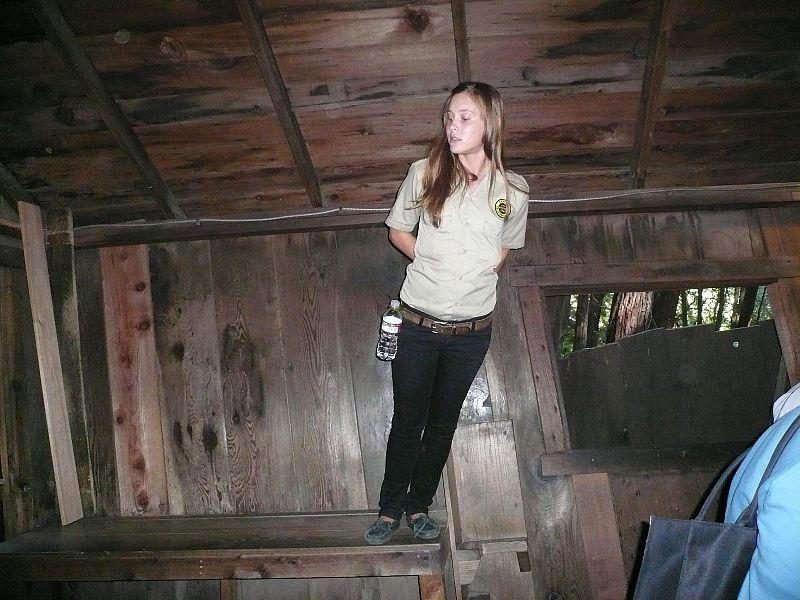 A guide at the Mystery Spot outside Santa Cruz appears to lean at an impossible angle while standing on a wonky table. (<a href="https://commons.wikimedia.org/wiki/File:Guide_leaning_on_table_at_The_Mystery_Spot.jpg">Briellecfarmer</a>/CC BY 4.0)