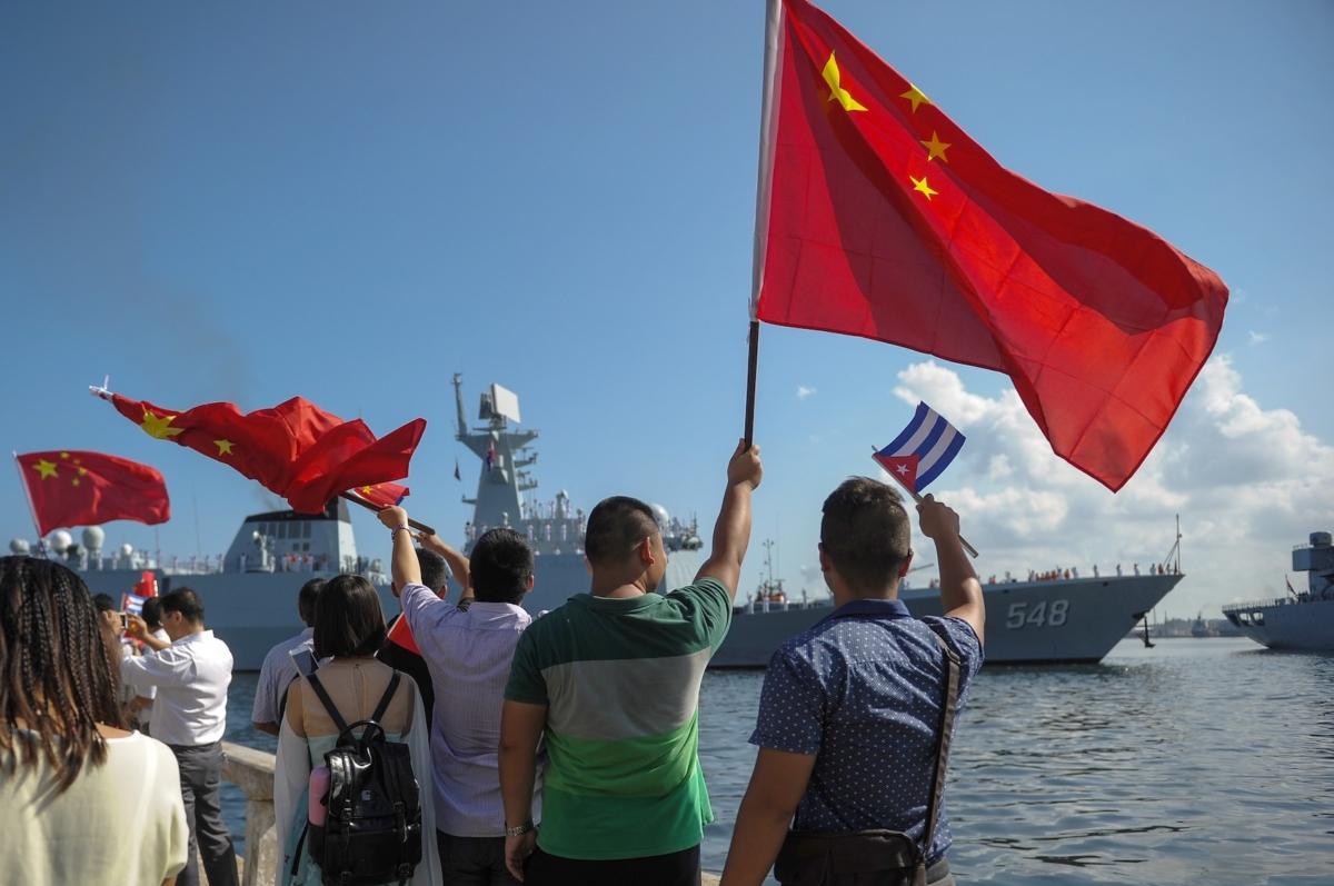 People wave Cuban and PRC flags as several Chinese Navy vessels enter the port of Havana on Nov. 10, 2015. (Yamil Lage/AFP via Getty Images)