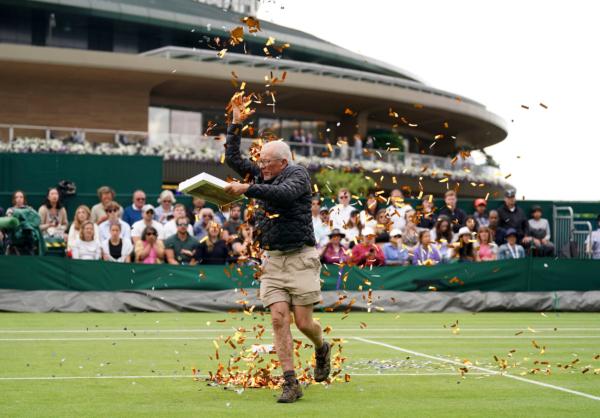 A Just Stop Oil protester on court 18 throwing confetti on to the grass during Britain's Katie Boulter's first-round singles match against Australia's Daria Saville on day three of the Wimbledon tennis championships in London, on July 5, 2023. (Adam Davy/PA via AP)