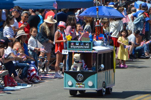 A dog in a mini bus passes by spectators at the 119th Fourth of July Parade in Huntington Beach, Calif., on July 4, 2023. (Alex Lee/The Epoch Times)