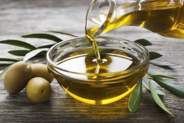 Bottle pouring virgin olive oil in a bowl close up. (DUSAN ZIDAR/Shutterstock)