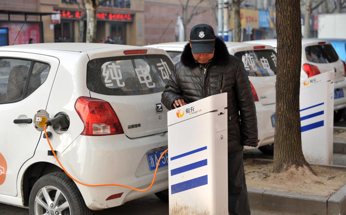 A man charges an electric vehicle in Linan, in east China's Zhejiang province, on March 2, 2016. (STR/AFP via Getty Images)