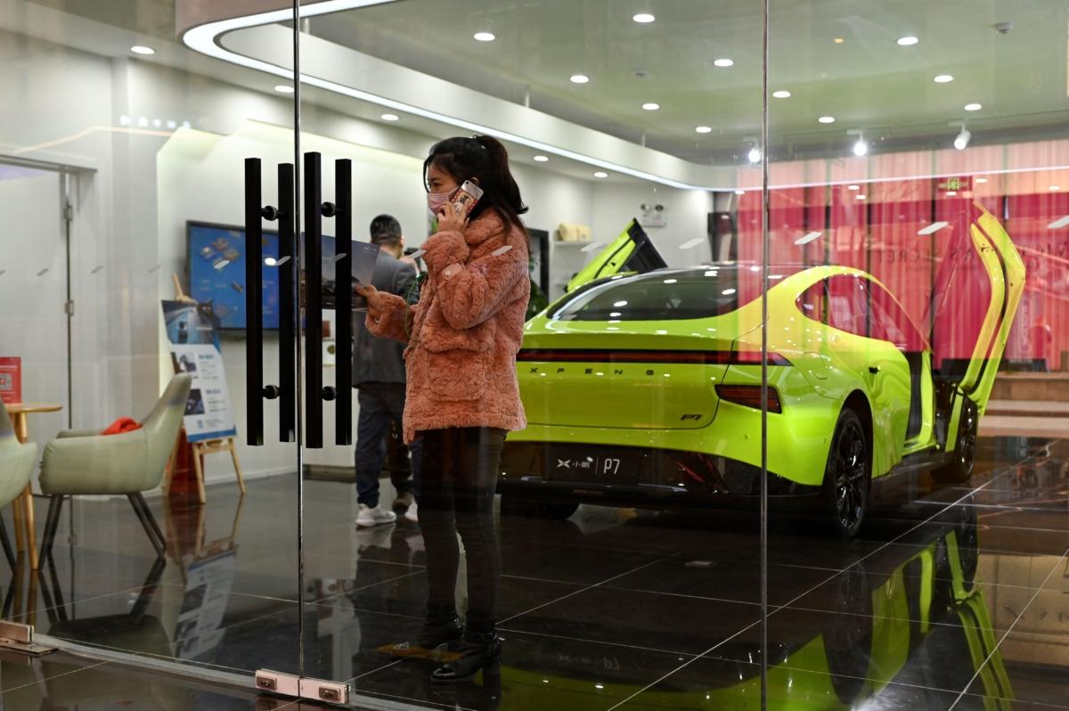 A woman uses her phone in a showroom of Xiaopeng Motors, a Chinese electric car manufacturer, in Beijing, on March 19, 2021. (Wang Zhao/AFP via Getty Images)