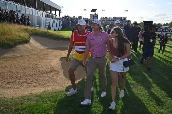 Australia's Cameron Smith (C) walks with his caddie (L) and girlfriend Shanel Naoum to collect his winner's trophy on the final day of the LIV Golf Invitational Series event at The Centurion Club in St Albans, north of London, on July 9, 2023. (Photo by JUSTIN TALLIS / AFP) (Photo by JUSTIN TALLIS/AFP via Getty Images)