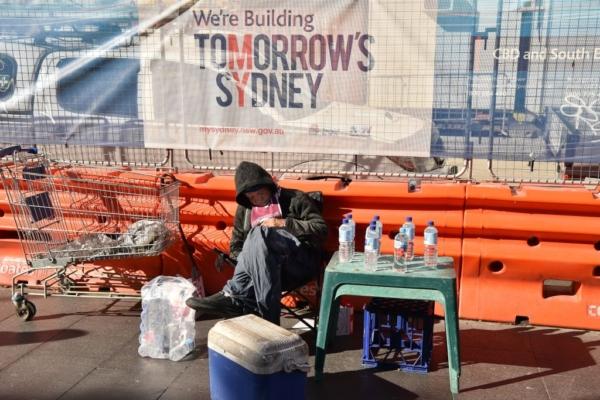A homeless man takes a nap from selling bottled water next to roadworks on a street in the central business district of Sydney, in Australia, on July 25, 2017. (Peter Parks/AFP via Getty Images)