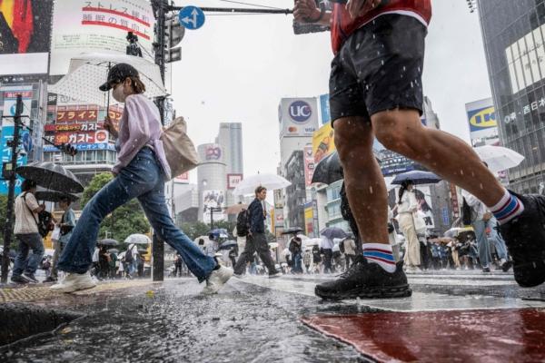 People use their umbrellas to shelter from the rain as they walk through Shibuya district in Tokyo on June 2, 2023. (YUICHI YAMAZAKI/AFP via Getty Images)