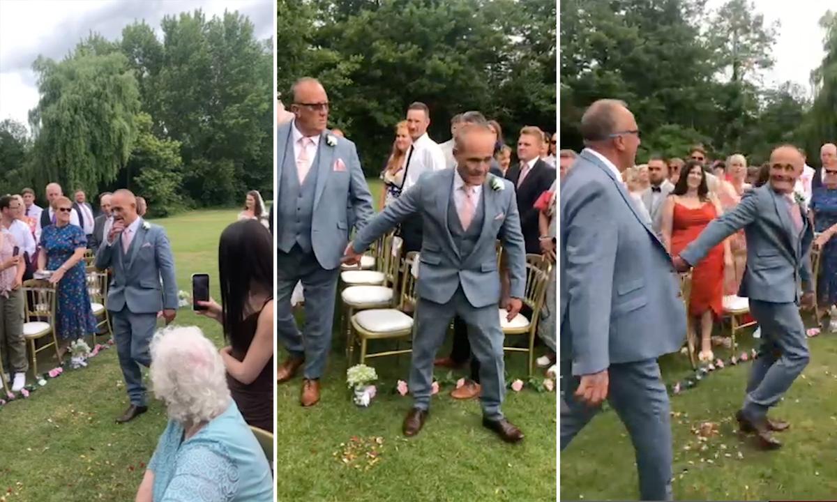 Dad Andy Collins, 58, grabs the hand of stepdad Jeff Bennett, 64, so they could both walk daughter Amy Walkinshaw, 31, down the aisle on her wedding day. (Screenshot/Newsflare)