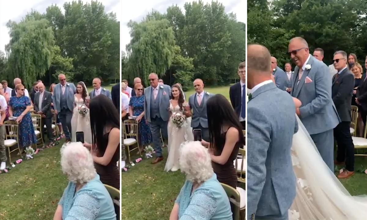 A clip captures dad Andy Collins, 58, and stepdad Jeff Bennett, 64, walking daughter Amy Walkinshaw, 31, down the aisle on her wedding day. (Screenshot/Newsflare)