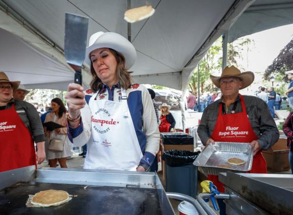 Alberta Premier Danielle Smith tosses pancakes over her shoulder at her Stampede pancake breakfast in Calgary, Alta., on July 10, 2023. (Jeff McIntosh/The Canadian Press)