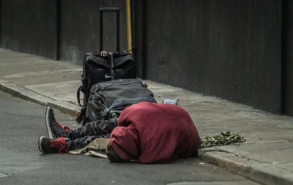 A homeless man lies on the streets of the Tenderloin District of San Francisco, Calif., on Feb. 23, 2023. (John Fredricks/The Epoch Times)
