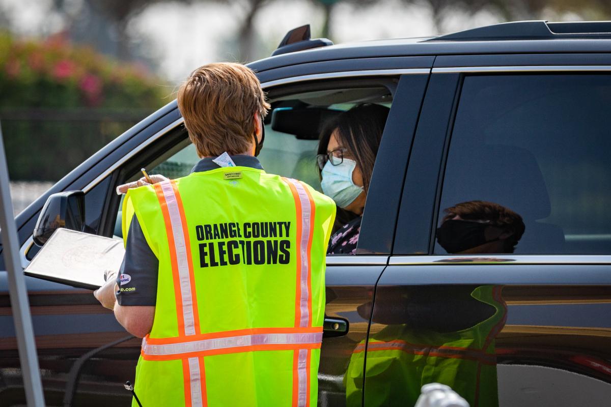 A worker assists drive-thru voters at The Honda Center in Anaheim, Calif., on Sept. 16, 2020. (John Fredricks/The Epoch Times)