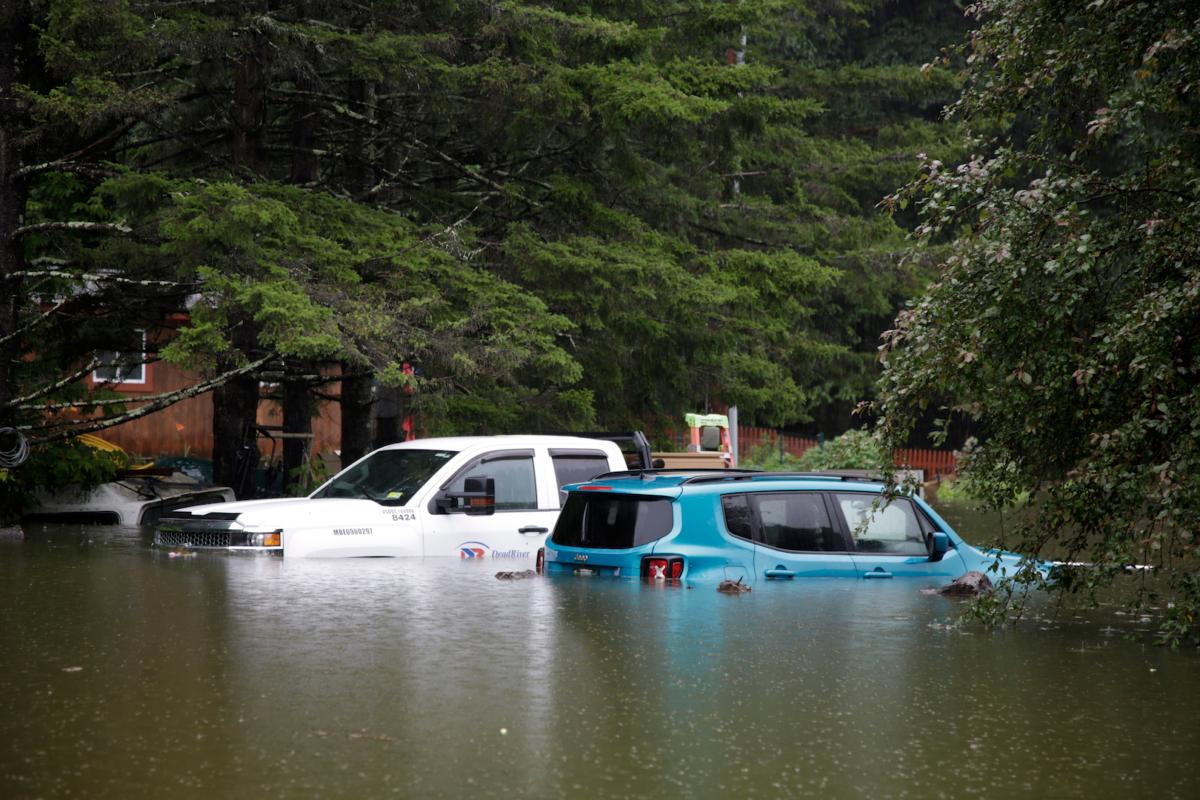Floodwaters rise in Bridgewater, Vt., on July 10, 2023, submerging parked vehicles and threatening homes near the Ottauquechee River. (Hasan Jamali/AP Photo)